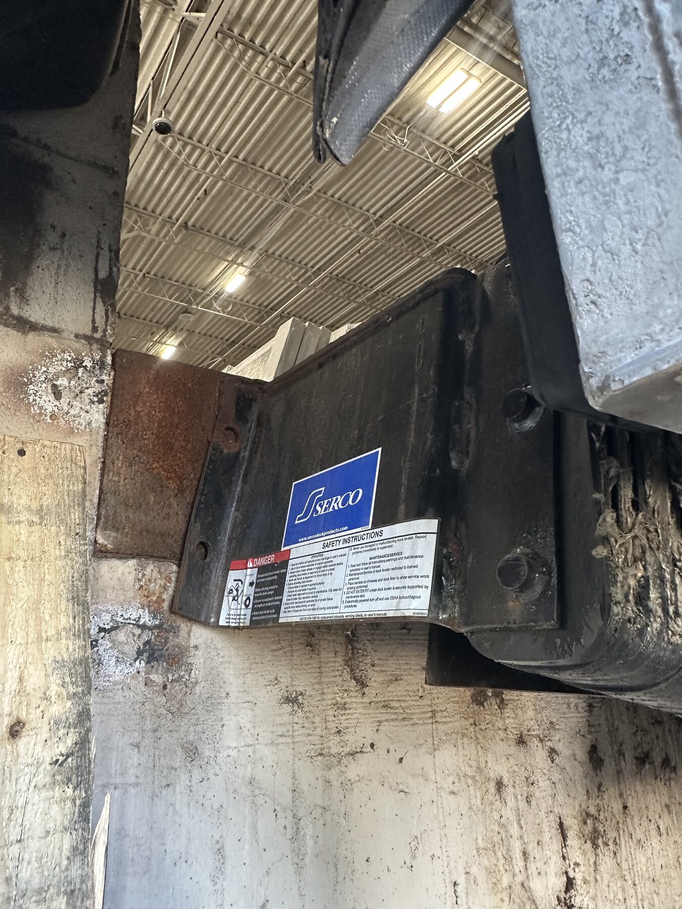 Damaged steel loading dock bracket before mobile welding repair